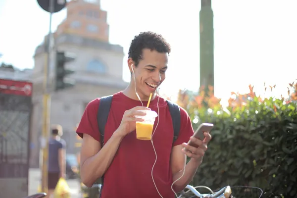 cheerful-man-with-smartphone-drinking-juice-on-str