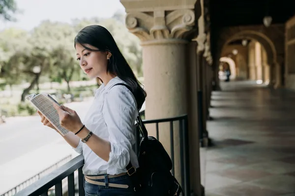 young elegant student woman reading textbook outsi