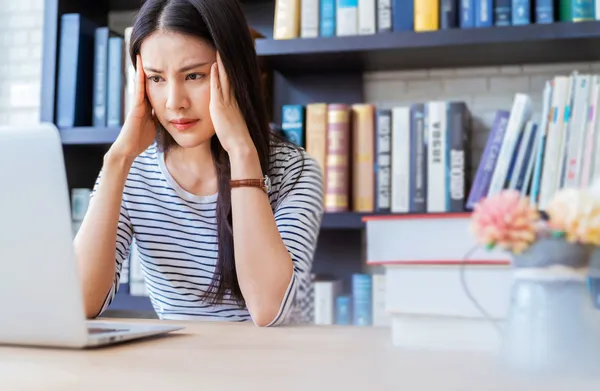 Pretty woman worries headache bookshelf work lapto