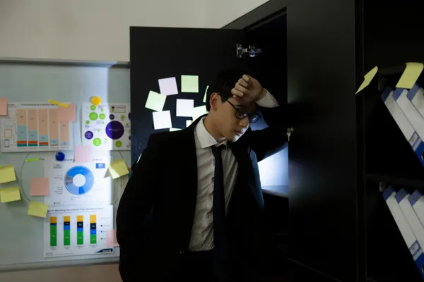 A tired office man is standing alone in a corner o